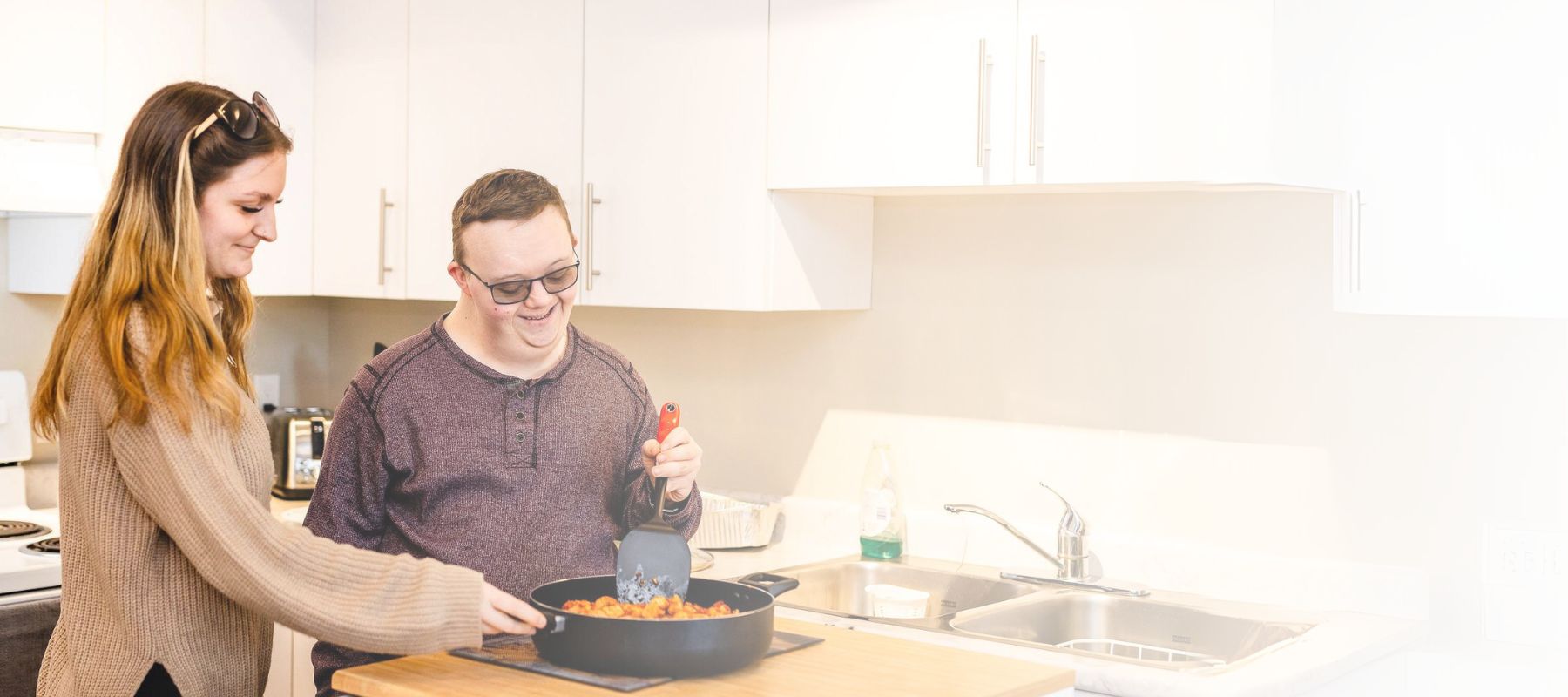 Individual with an intellectual disability and his support worker cooking in the kitchen - inclusion powell river
