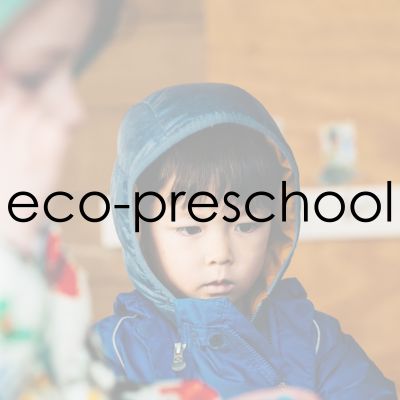 A young boy in a blue rain suit with the words eco-preschool overlayed