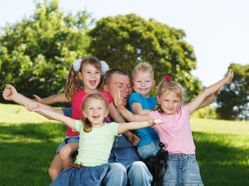 A father playing with his four children outside - one with an intellectual disability - inclusion powell river